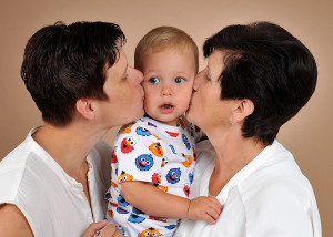 Mama und Oma küssen Kind